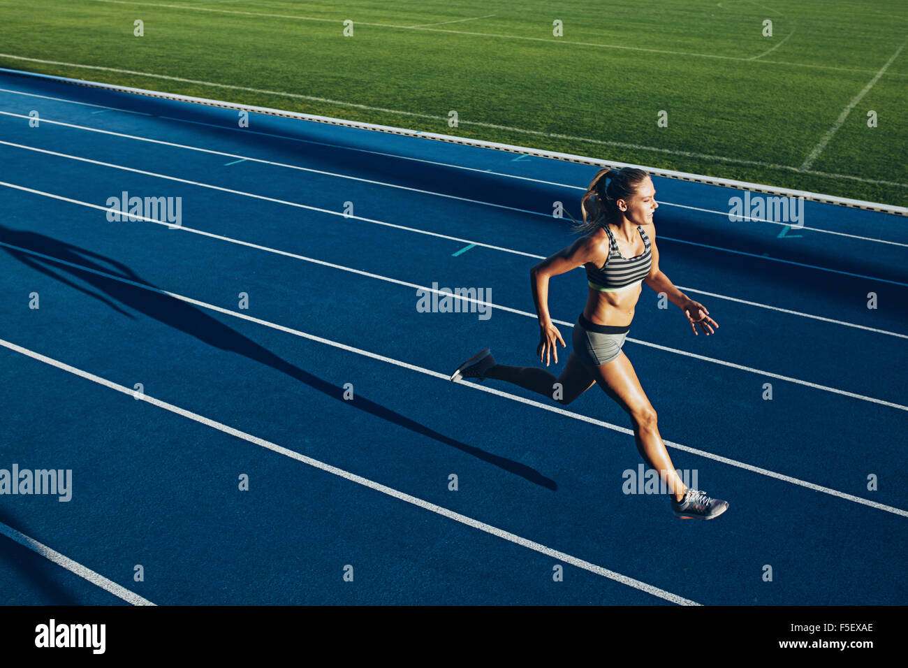 Jeune femme tournant sur racetrack au cours de session de formation. Coureuse pratiquer l'athlétisme sur piste de course. Banque D'Images Jeune femme tournant sur racetrack au cours de session de formation. Coureuse pratiquer l'athlétisme sur piste de course. Banque D'Images
