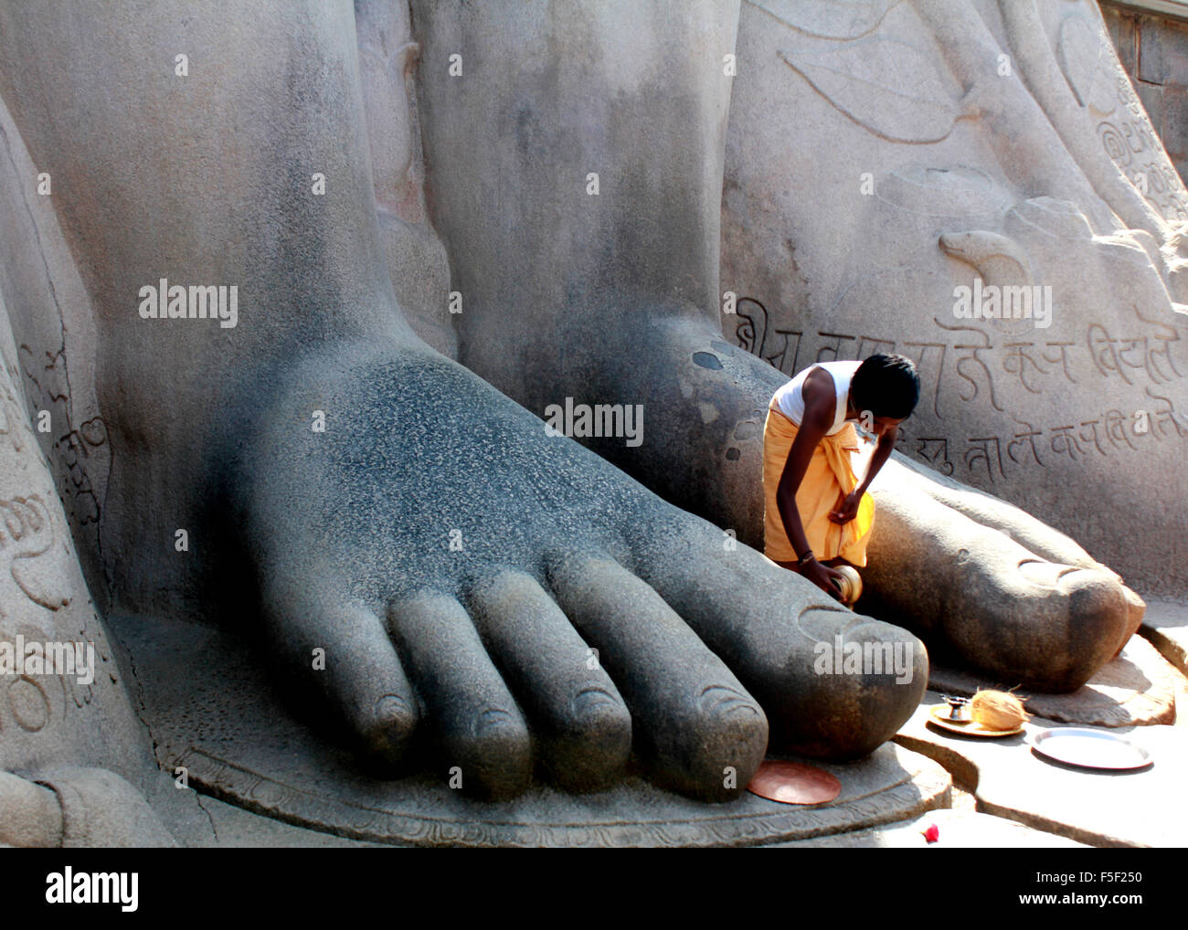 Un jeune prêtre prosterné aux pieds de Gommateshwara bahubali à Shravanabelagola Hassan dans le district de Karnataka, Inde Banque D'Images