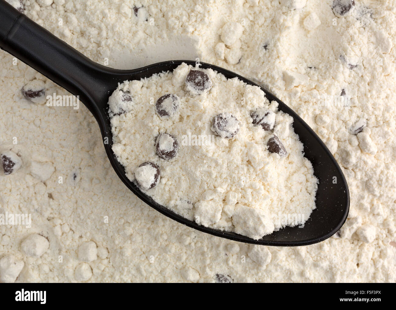 Top View of dry chocolate chip cookie mix dans une cuillère noire sur le dessus du mélange plus éclairé par la lumière naturelle. Banque D'Images