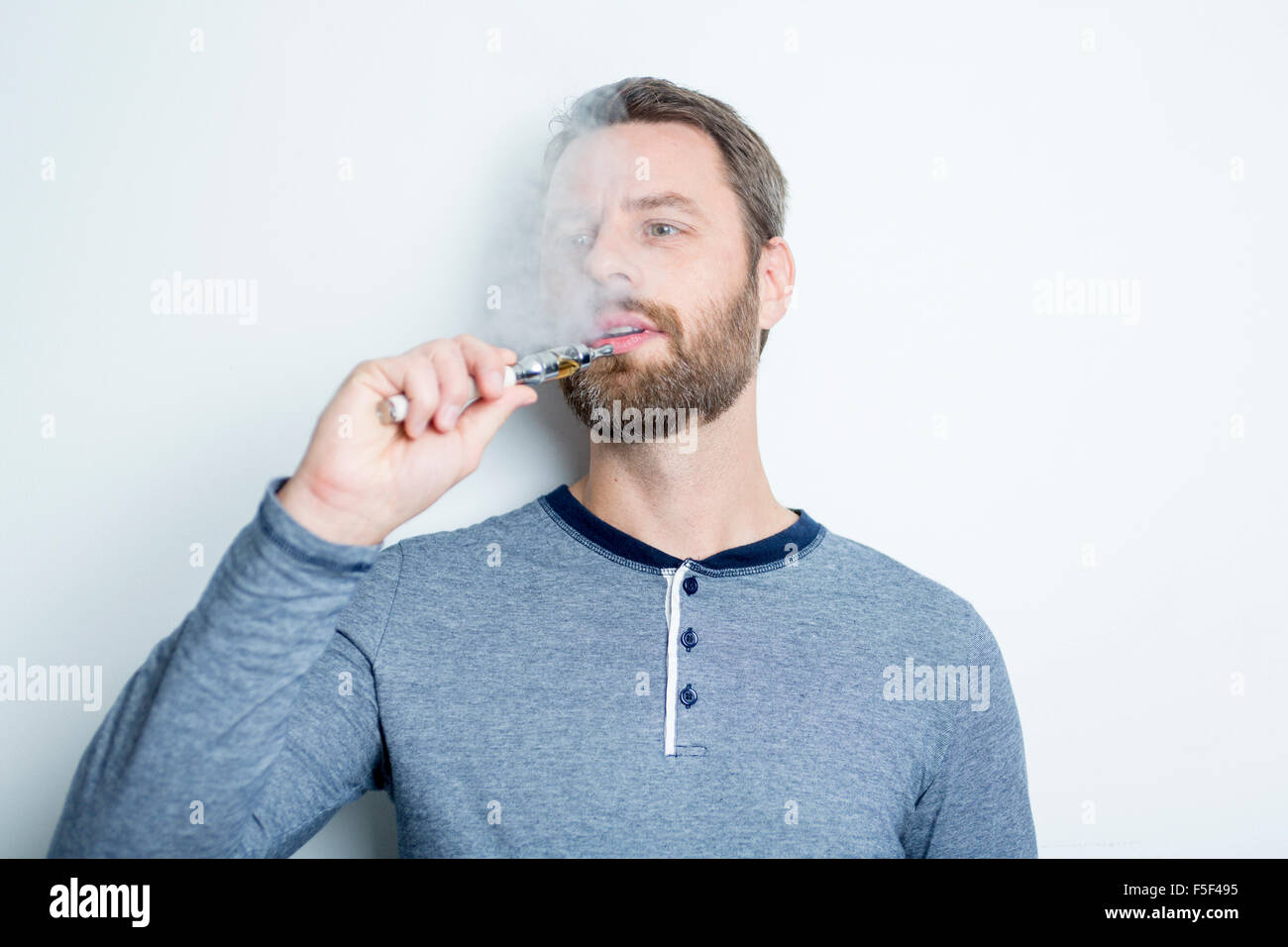 Portrait d'un jeune homme qui fume cigarette électrique Banque D'Images