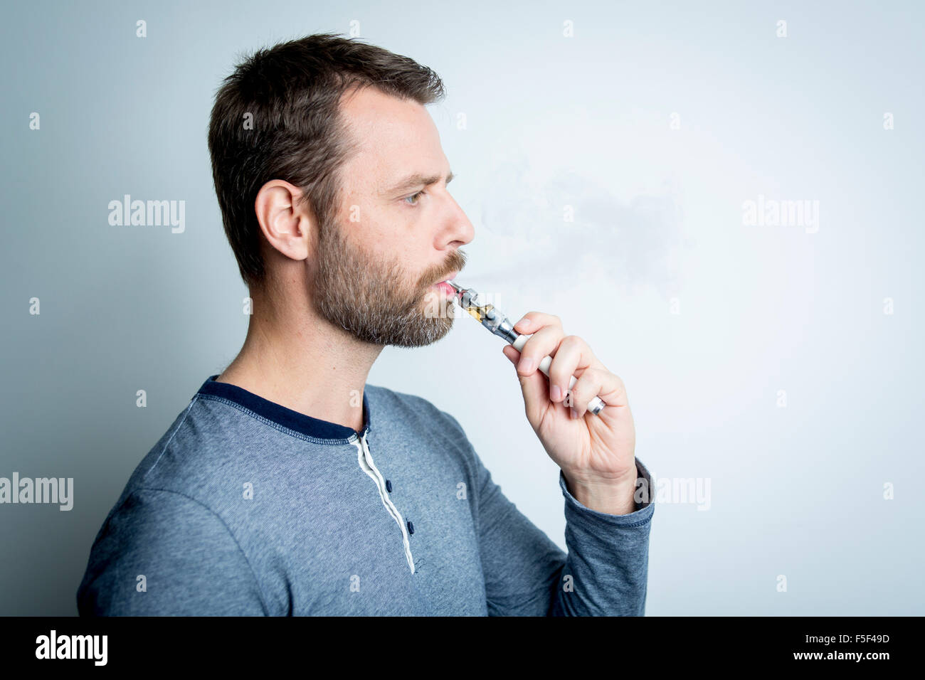 Portrait d'un jeune homme qui fume cigarette électrique Banque D'Images