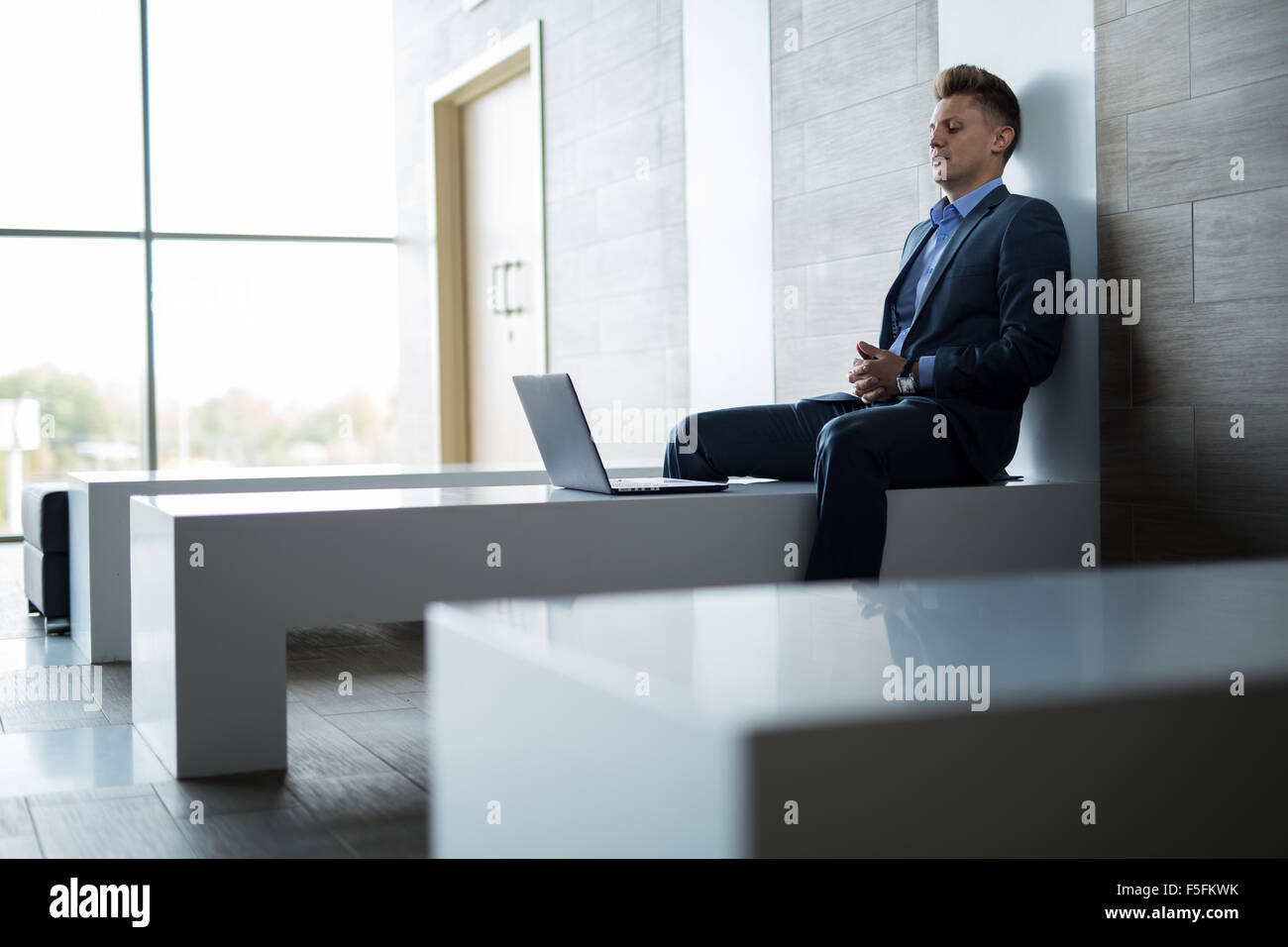 L'homme d'affaires assis seul sur un banc avec coffre Banque D'Images