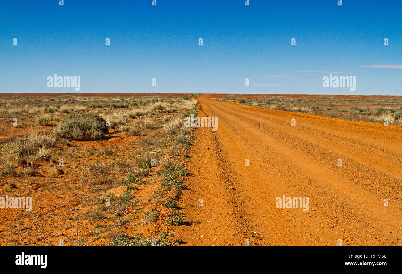 Longue route de terre en Australie s'étendant à travers les zones arides plaines déboisées de Flinders région désertique à horizon lointain et ciel bleu Banque D'Images