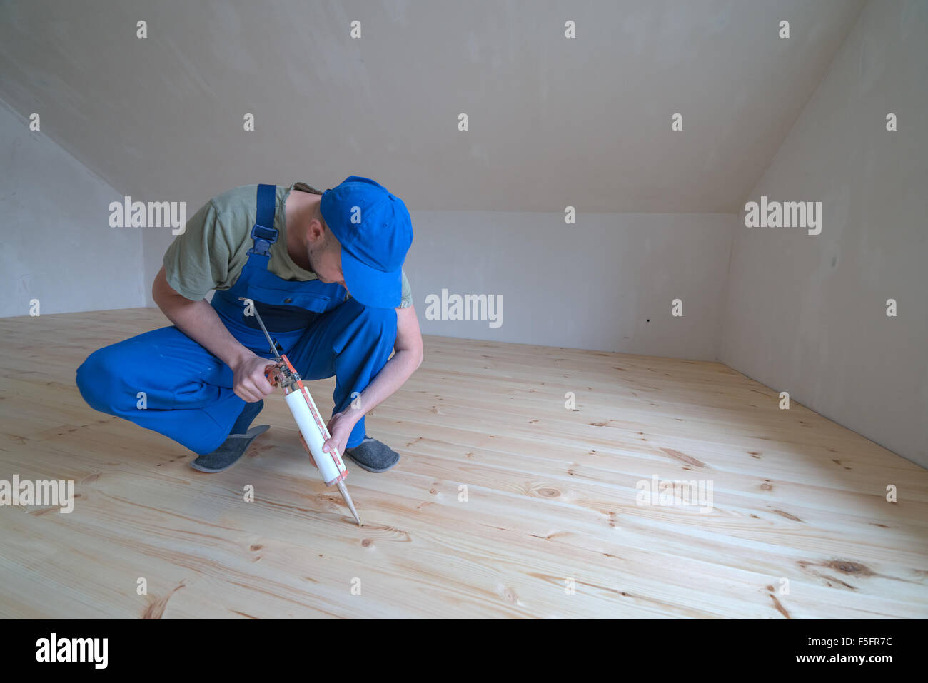 Plancher en bois vernis. Travailleur avec des armes à feu en silicium. Banque D'Images