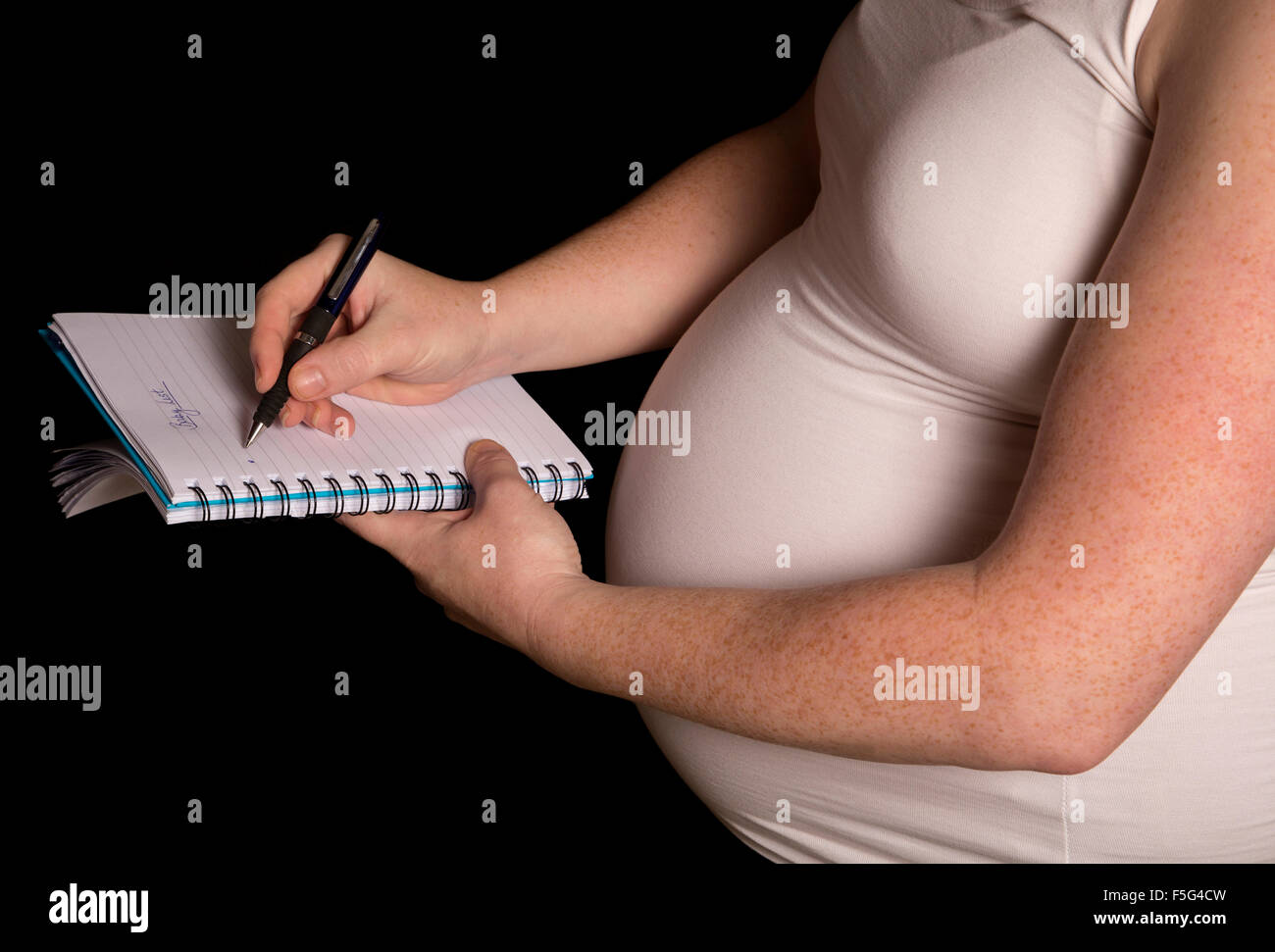 Les femmes enceintes la rédaction d'une liste de bébé sur fond noir Banque D'Images