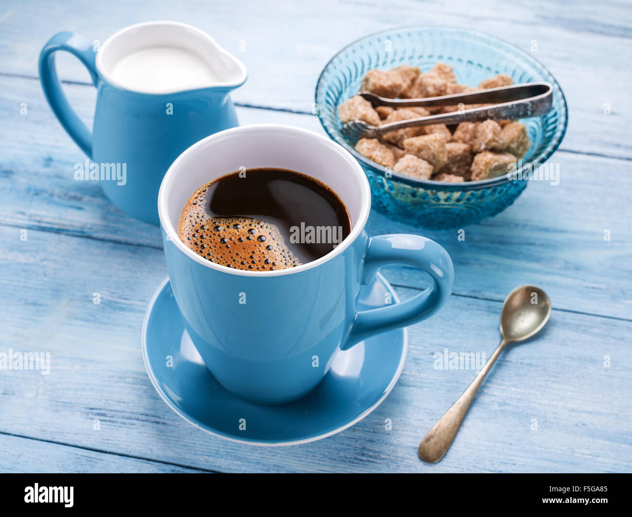 Tasse de café, lait et sucre de canne glaçons sur la vieille table en bois. Banque D'Images