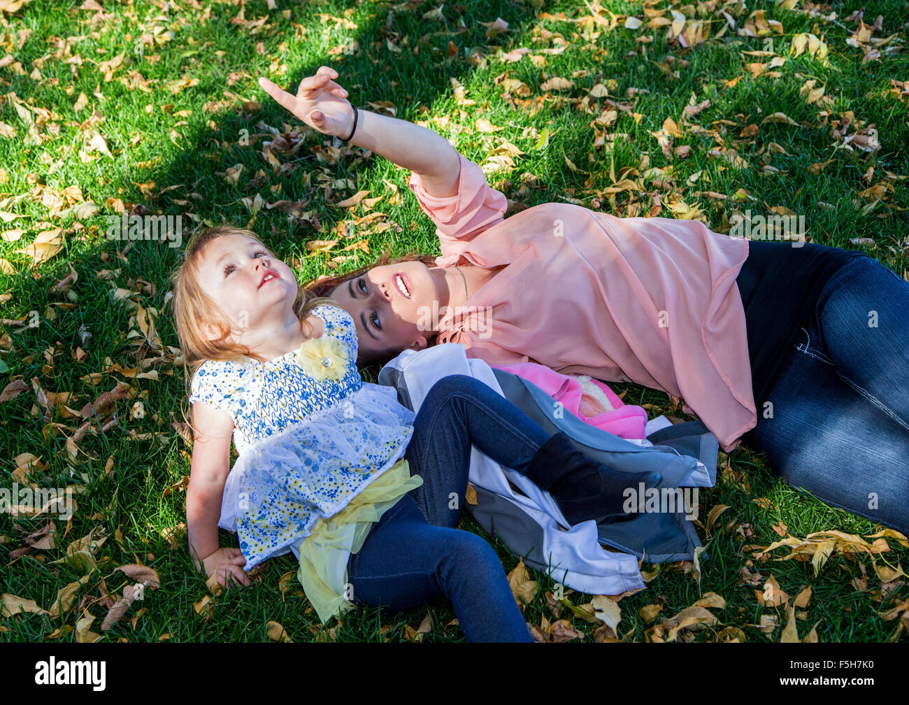 Belle mère jouant dans l'herbe avec jeune fille, town park Banque D'Images