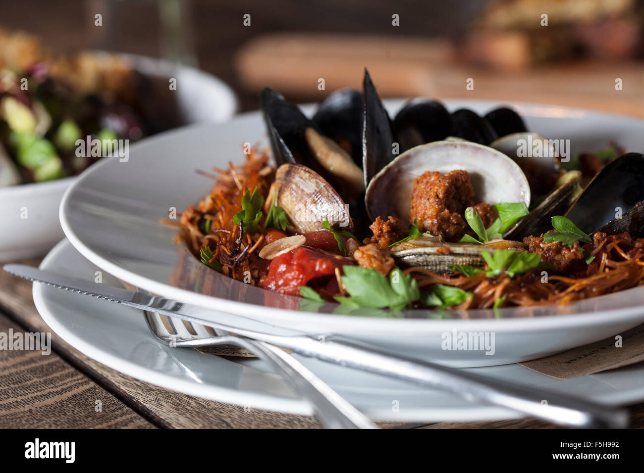 Close-up de moules, palourdes, des pâtes sur une plaque blanche avec fourchette et couteau Banque D'Images