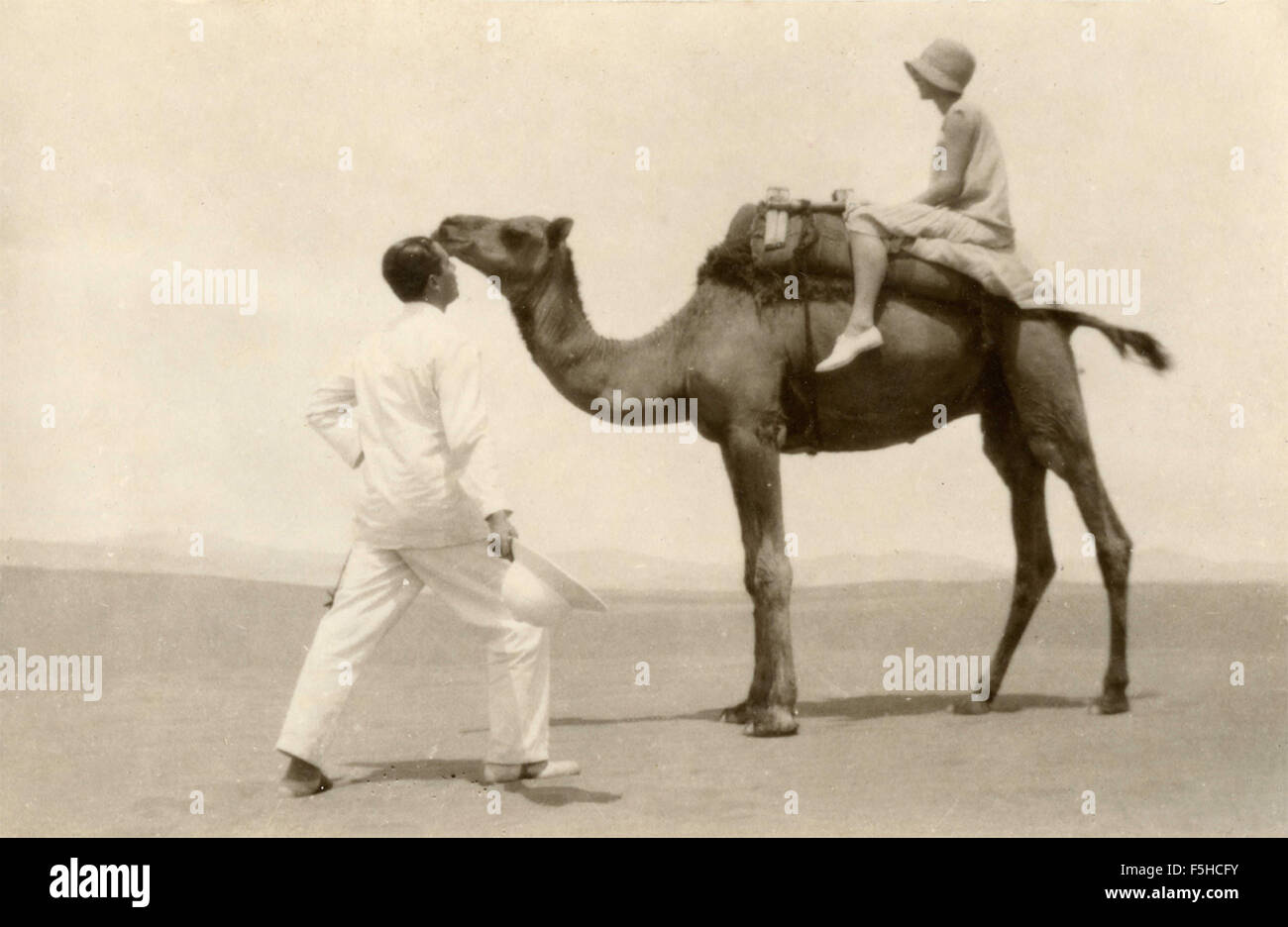Un homme à côté d'une femme sur un chameau dans le désert Banque D'Images