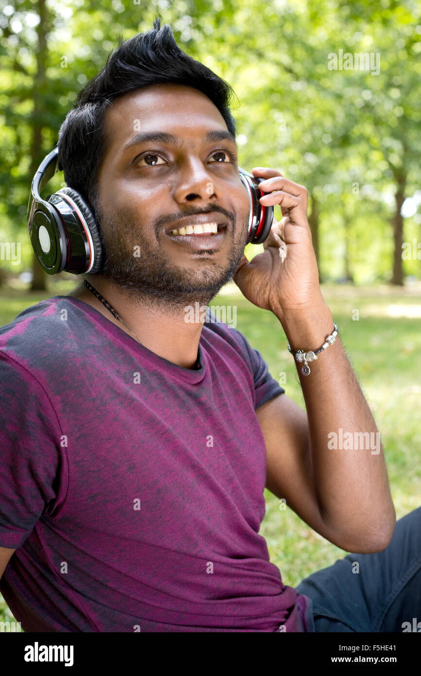 Heureux jeune homme écoute de la musique dans le parc Banque D'Images