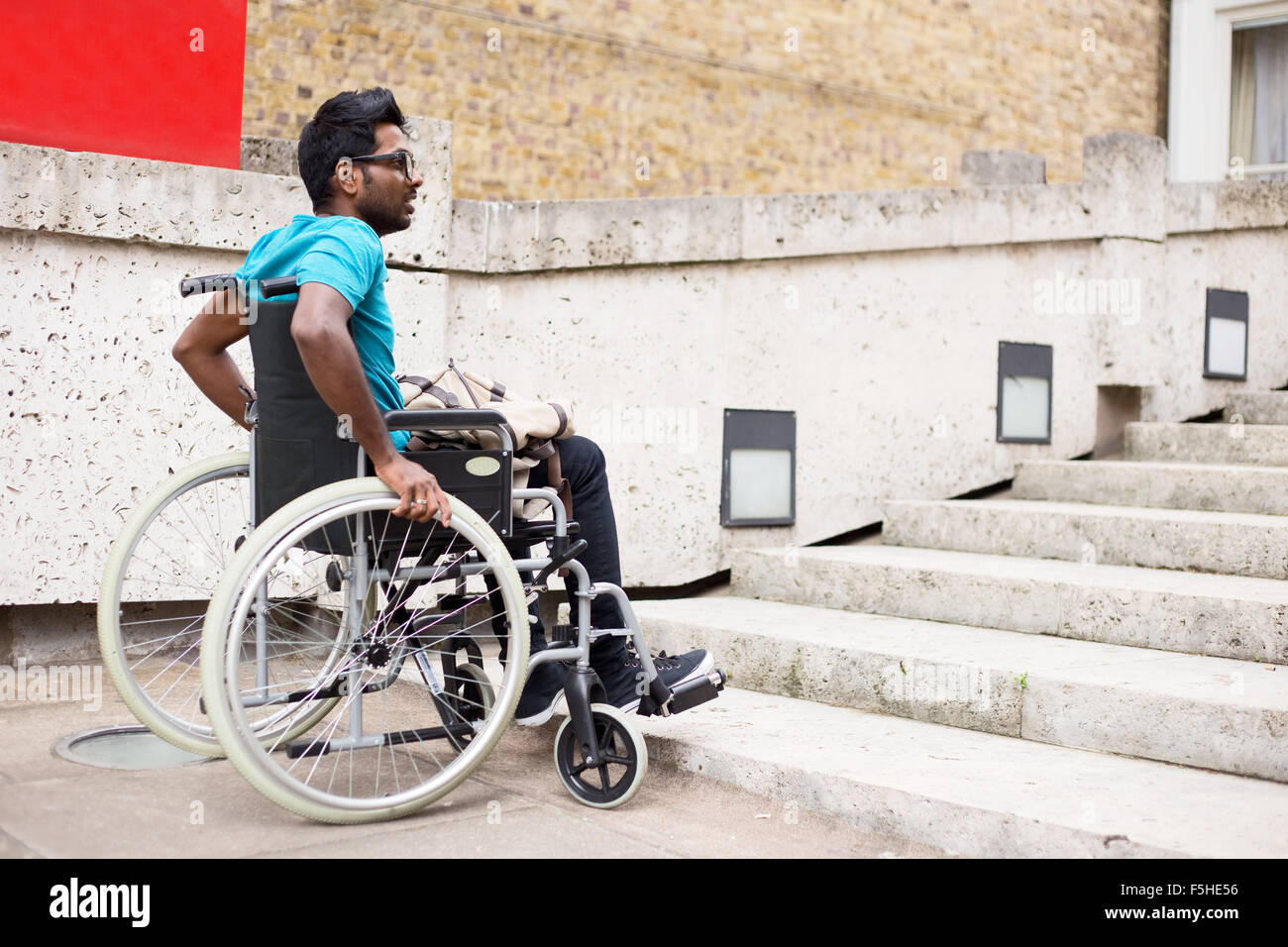 Homme handicapé dans un fauteuil roulant au bas d'étapes Banque D'Images
