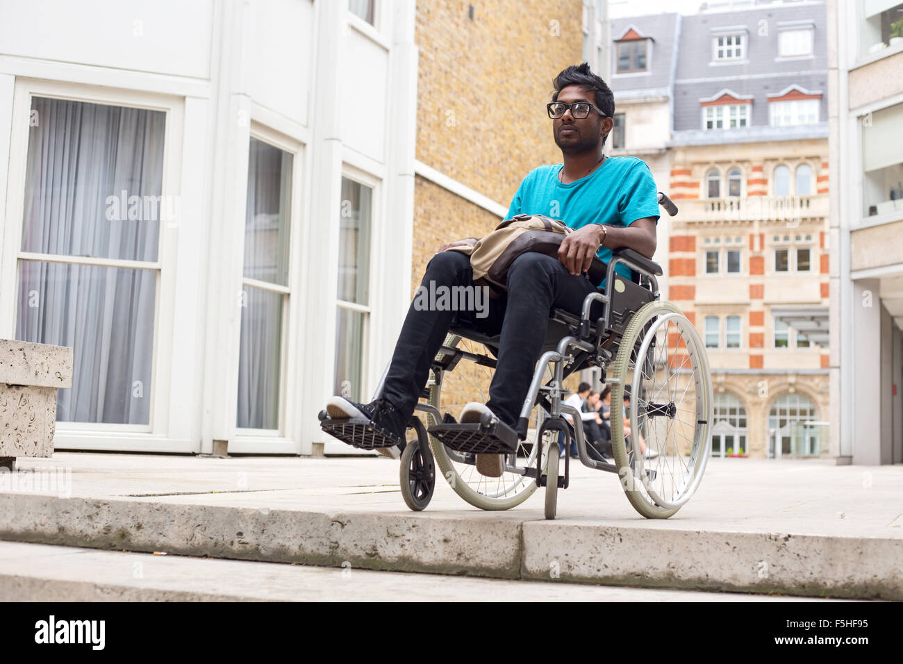 Jeune homme en fauteuil roulant en haut d'étapes Banque D'Images