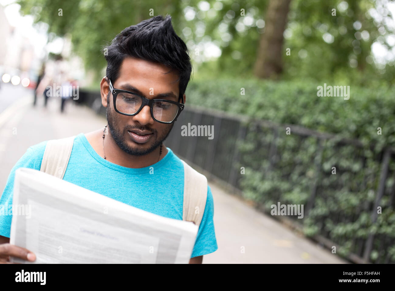 Jeune Indien homme lisant le journal dans la rue Banque D'Images