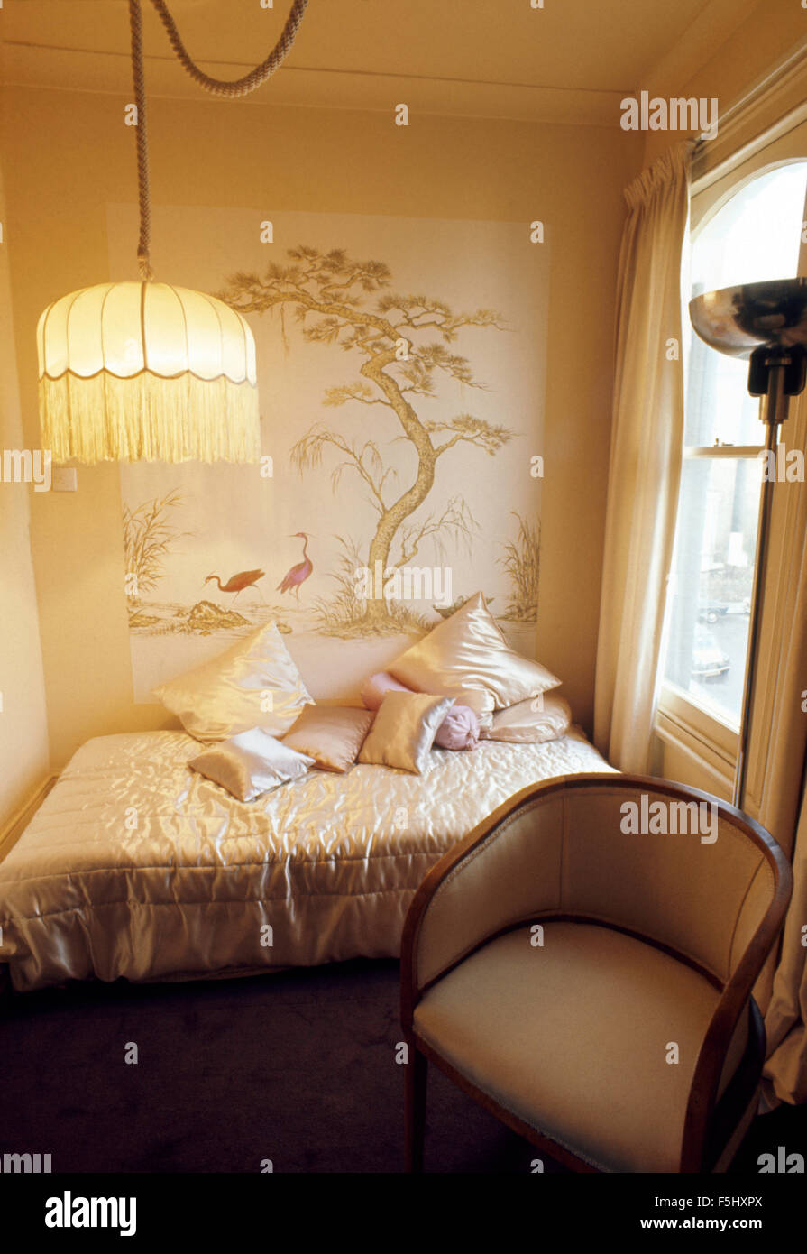 Abat-jour à franges sur le raccord lumière dans les petites années 70 chambre avec un couvre-lit en satin on bed Banque D'Images