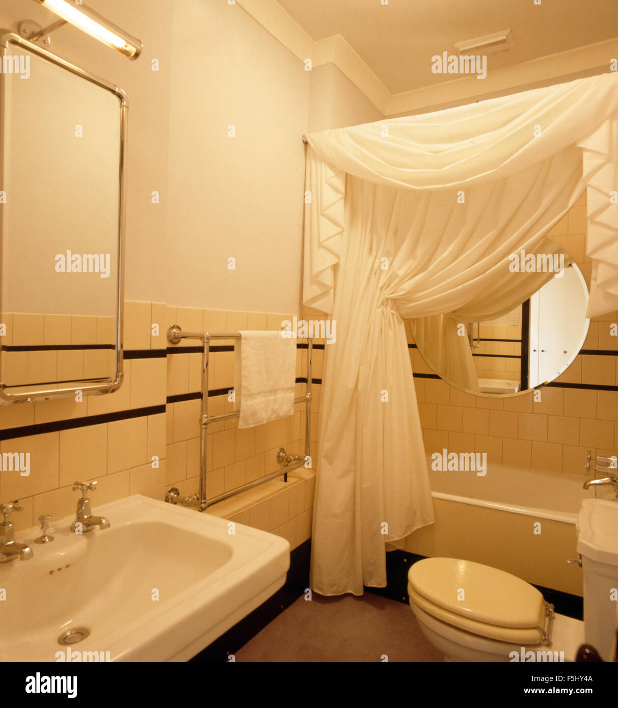 Rideaux blancs sur baignoire dans salle de bains de style années 30 Banque D'Images