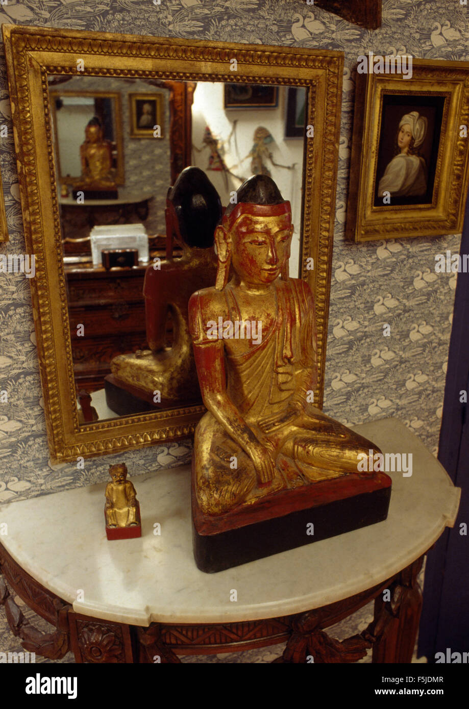 Statue asiatique doré recouvert de marbre sur une table console dans un hall des années 60 Banque D'Images