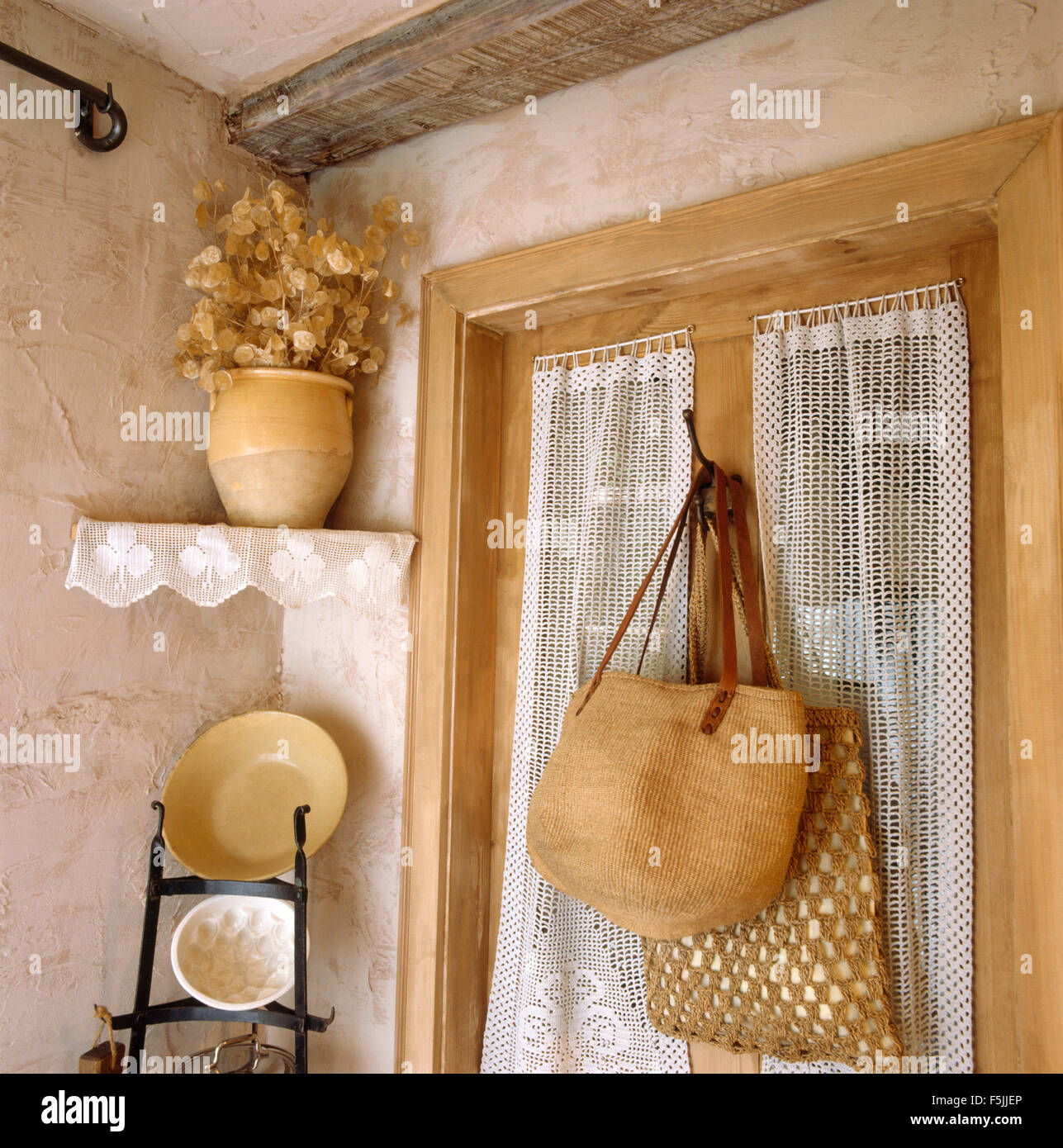 Sacs en raphia tissé sur une porte avec un rideau de dentelle en coin de  cuisine années 80 Photo Stock - Alamy