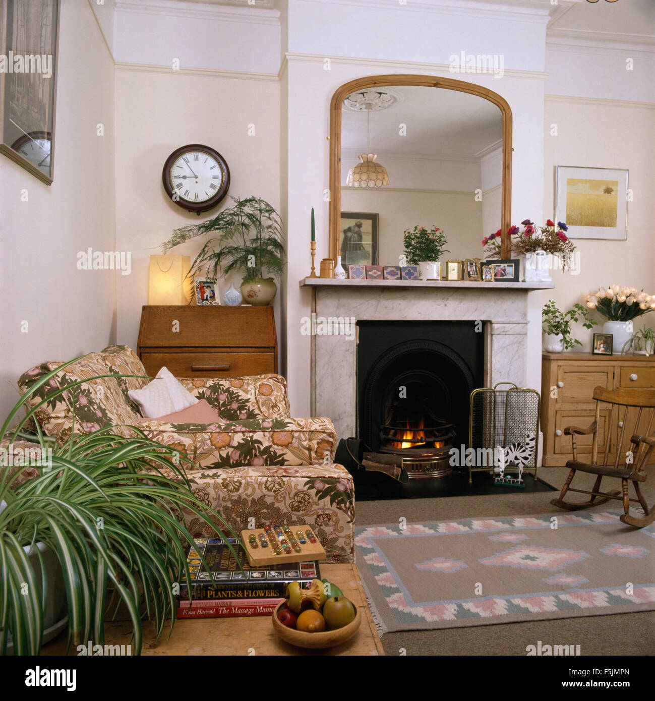 Miroir au-dessus de cheminée en marbre avec feu allumé dans années 90 salon Banque D'Images