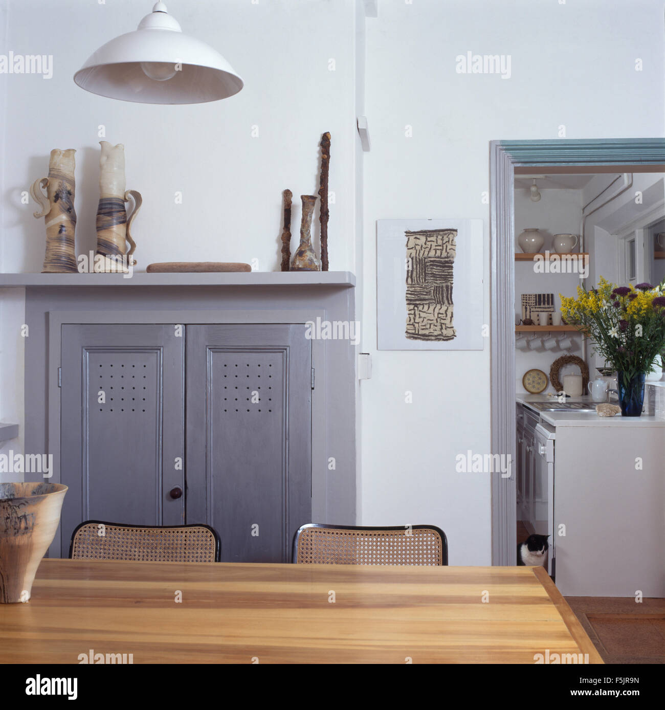 Portes en bois gris sur meuble dans une cheminée dans une salle blanche avec porte de cuisine Banque D'Images