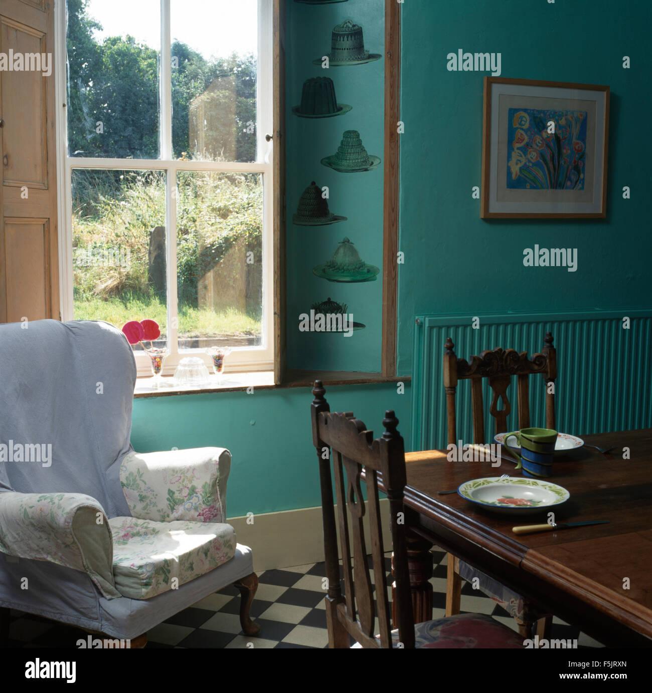 Lâche sur aile capot blanc chaise à côté fenêtre dans un pays turquoise salle à manger avec table et chaises en bois foncé Banque D'Images