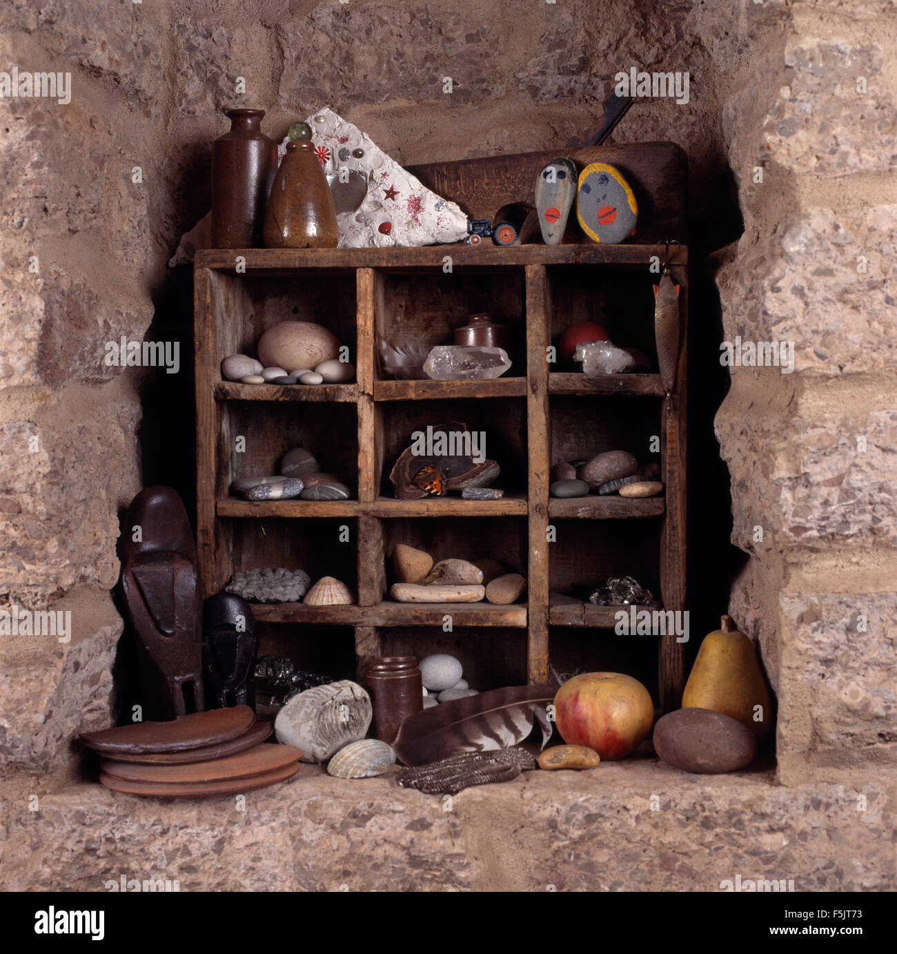 Close-up d'une collection de cailloux et des objets trouvés sur les étagères en bois rustique dans une alcôve Banque D'Images