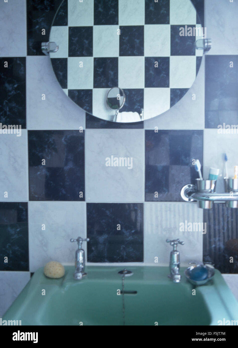Miroir circulaire au-dessus du bassin de style années 40 turquoise pâle dans un noir +blanc salle de bains rétro Banque D'Images