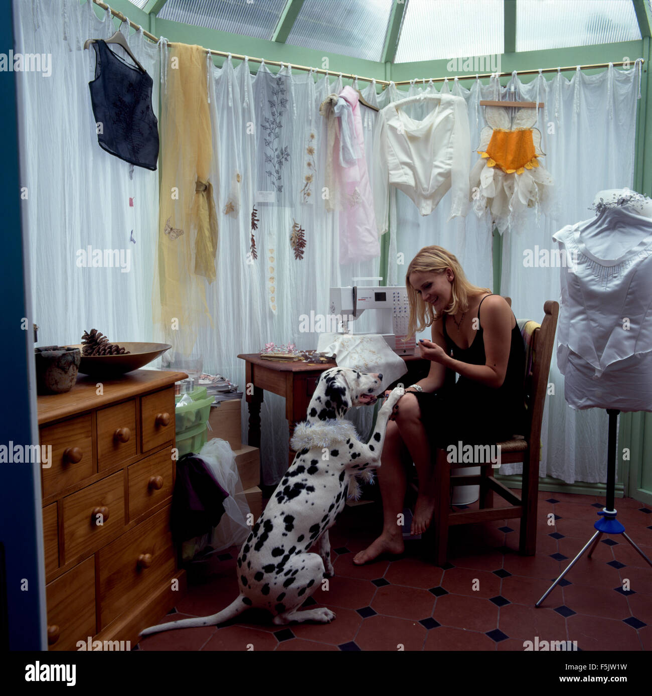 Jeune femme jouant avec un chien dalmatien dans un atelier des années 90 pour un usage éditorial uniquement Banque D'Images