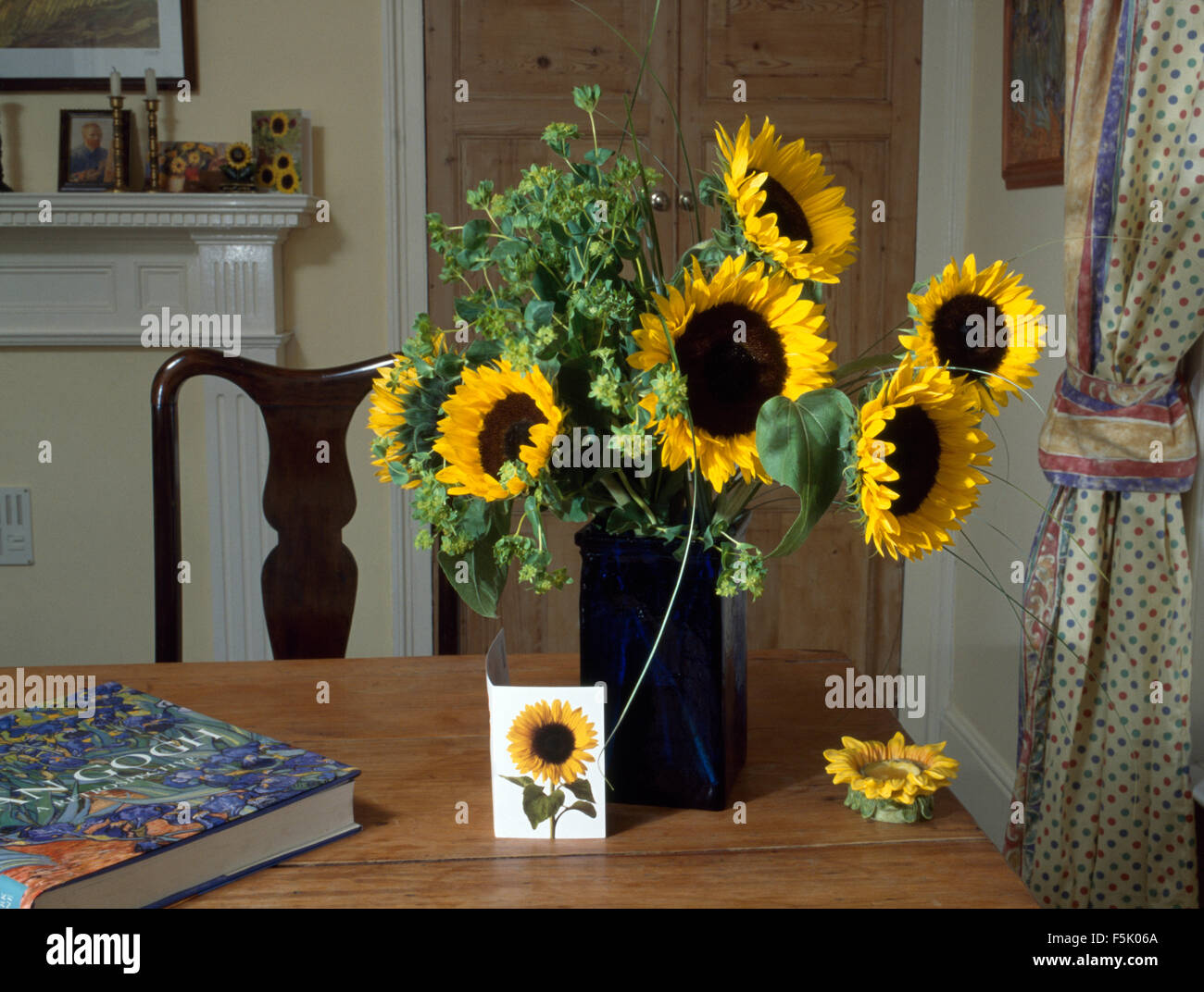 Vase de tournesols jaunes sur la table de salle à manger avec un grand dos dur livre et une carte de tournesol Banque D'Images