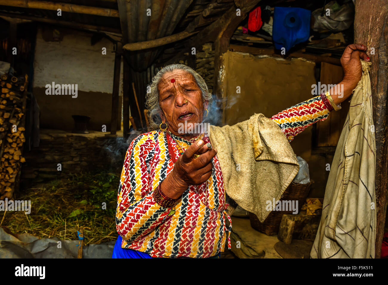 Vieille Femme fumant une cigarette tout en parlant dans sa maison. Banque D'Images