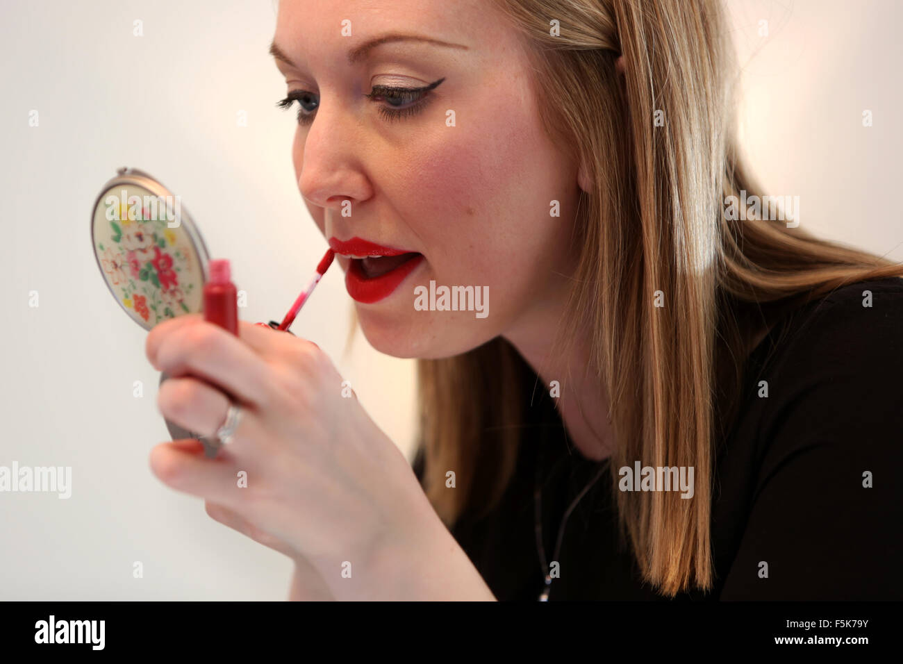 Jeune jolie fille d'appliquer le rouge à lèvres rouge à lèvres à Worthing, West Sussex, UK. Banque D'Images
