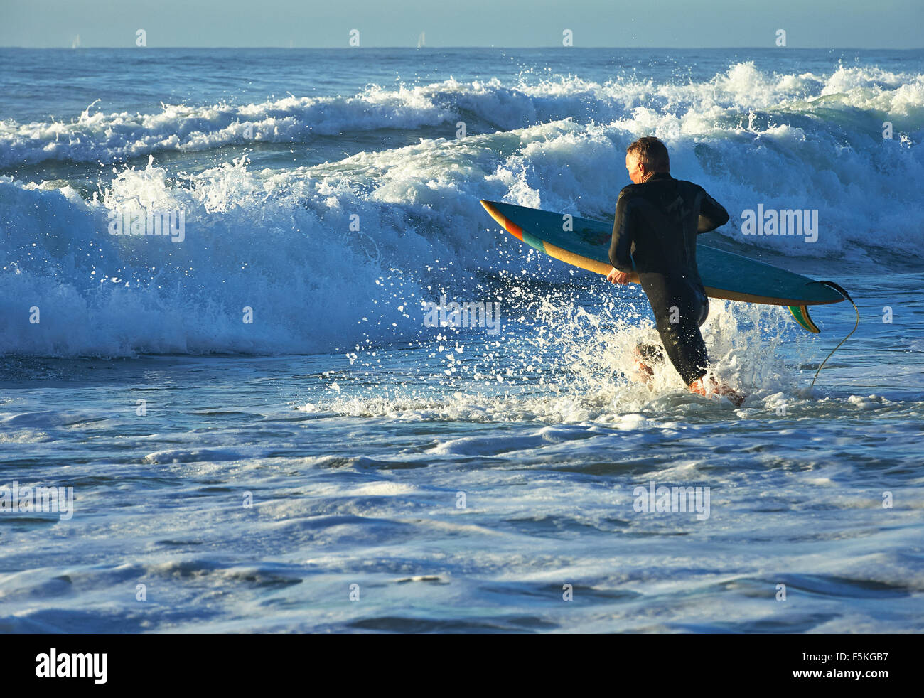 Homme qui court à une vague de rompre avec un surf Banque D'Images