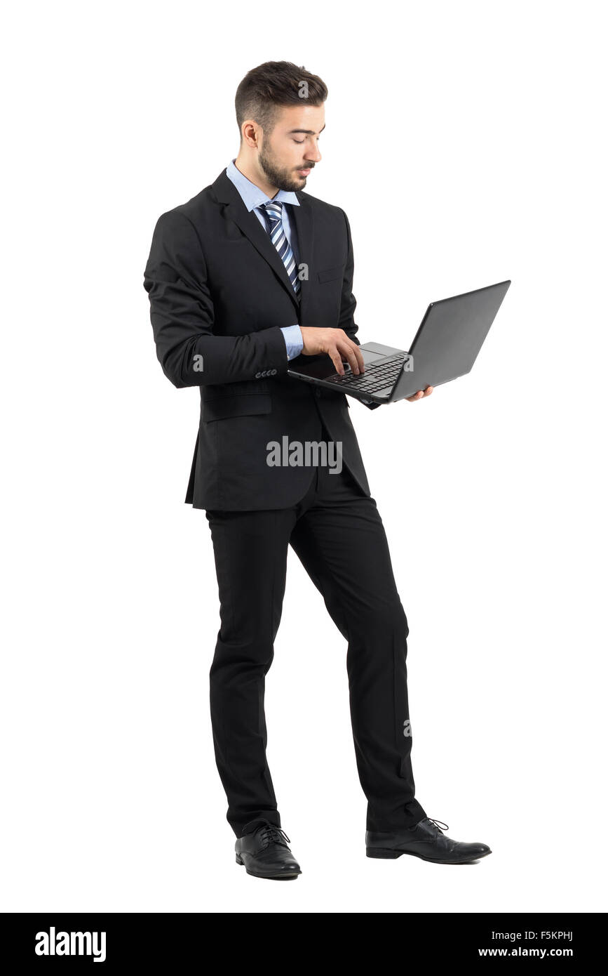 Side view of young businessman in suit à l'aide d'ordinateur portable. La pleine longueur du corps portrait studio isolated over white background Banque D'Images