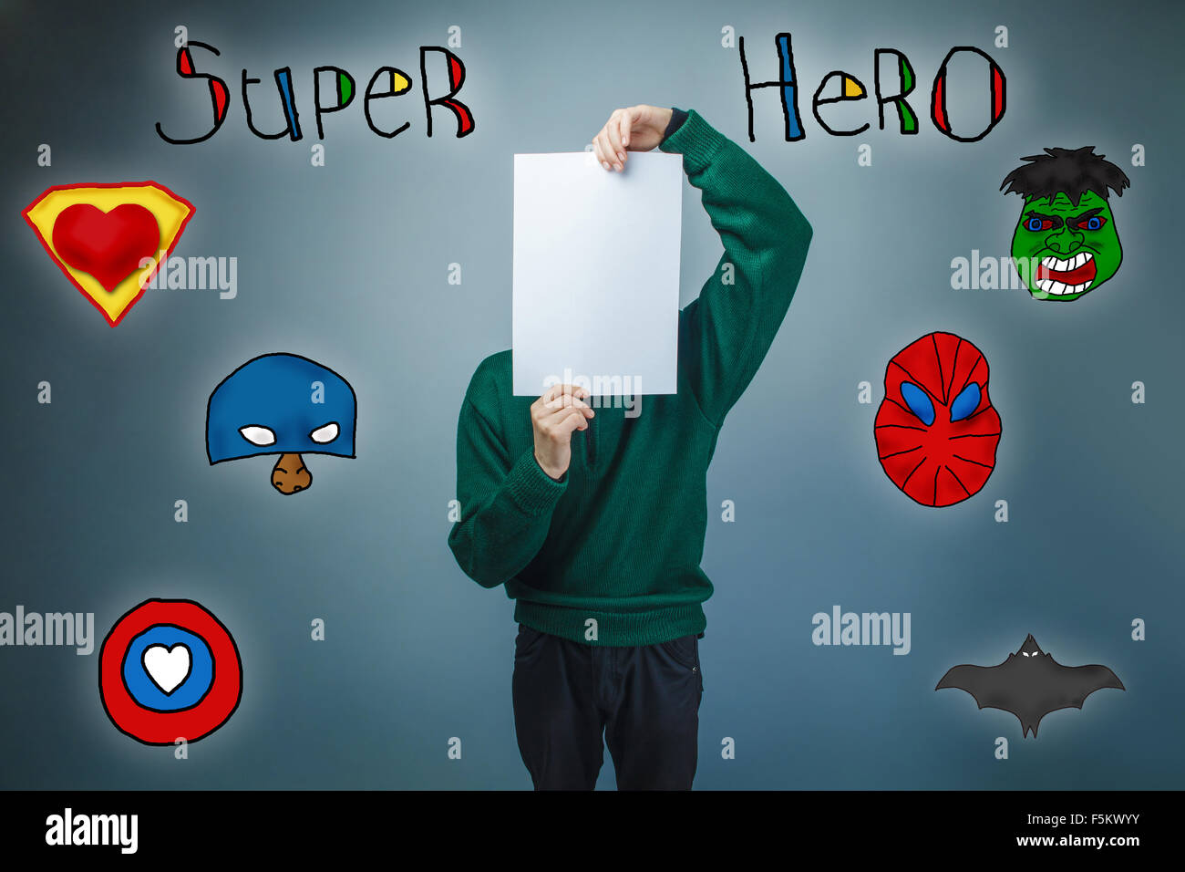 Garçon en chandail vert tenant une feuille de papier propre superhe Banque D'Images