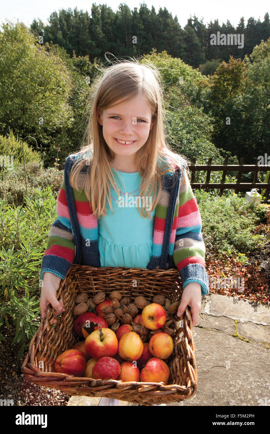 Jeune fille posant avec un panier de fruits cueillis à la main Banque D'Images