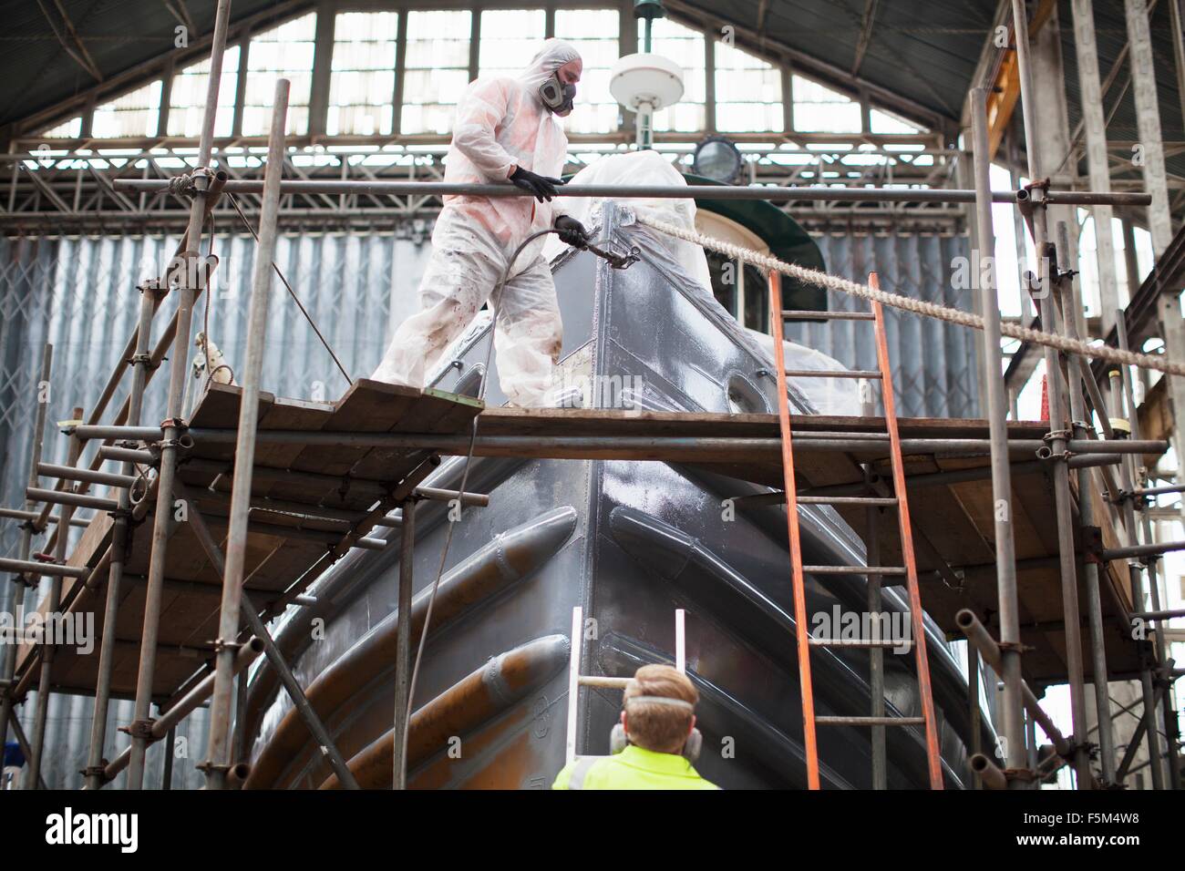 Peinture par pulvérisation des travailleurs du chantier naval en bateau Banque D'Images