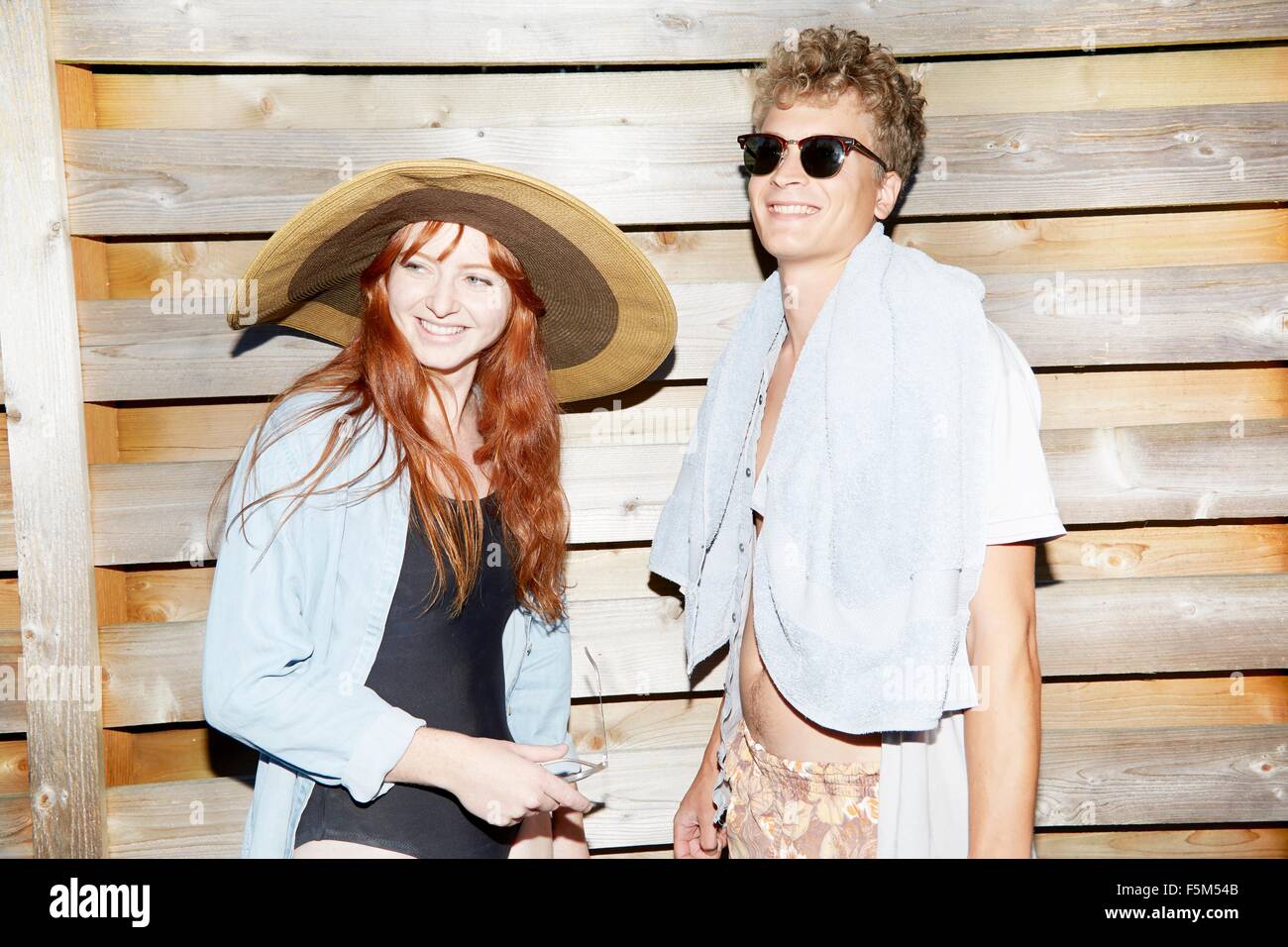 Jeune couple portant des maillots de bain en face de clôture Banque D'Images