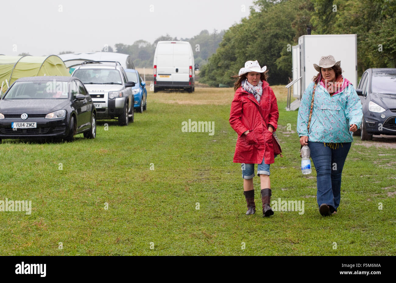 Deux femmes en chapeaux de cow-boy à marcher en direction de la caméra sur  un camping humide Photo Stock - Alamy