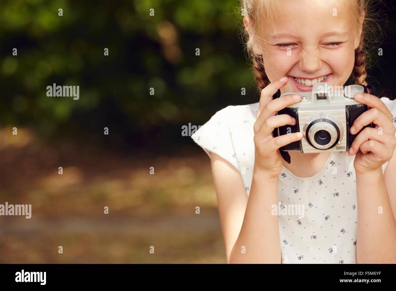 Portrait of Girl holding film appareil les yeux fermés smiling Banque D'Images
