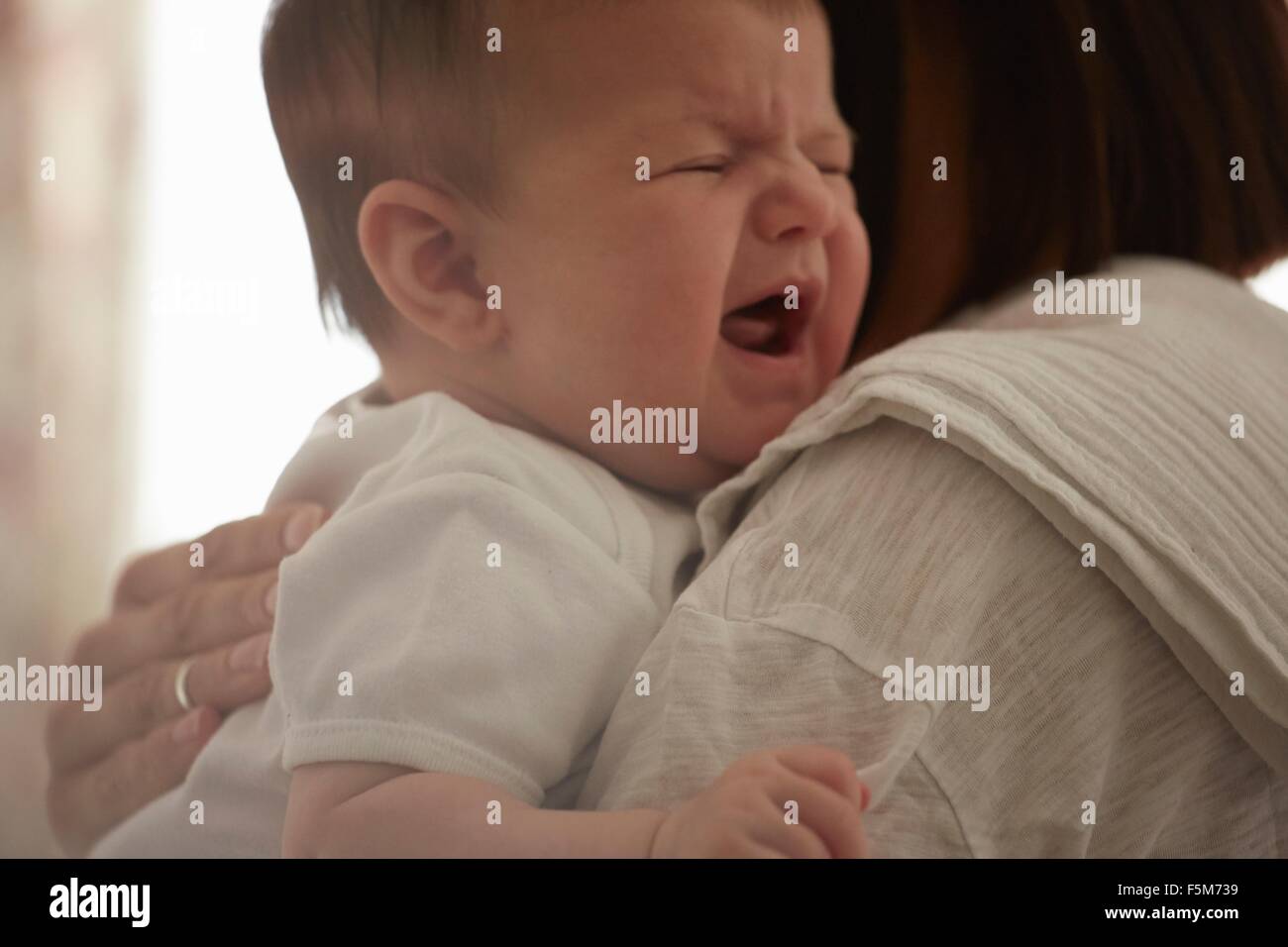 Mère portant bébé qui pleure Banque D'Images