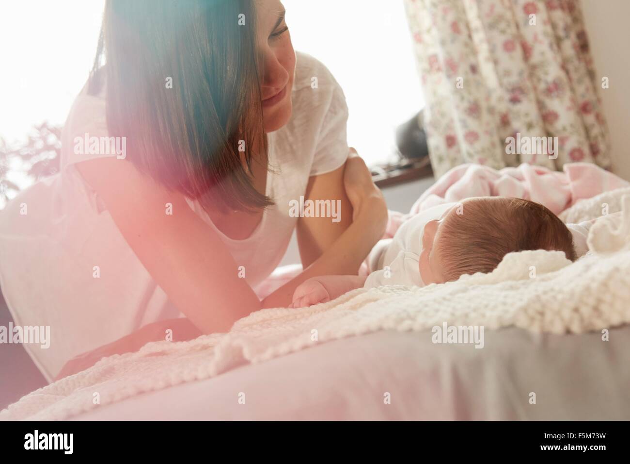 Mère jouer avec bébé au lit Banque D'Images