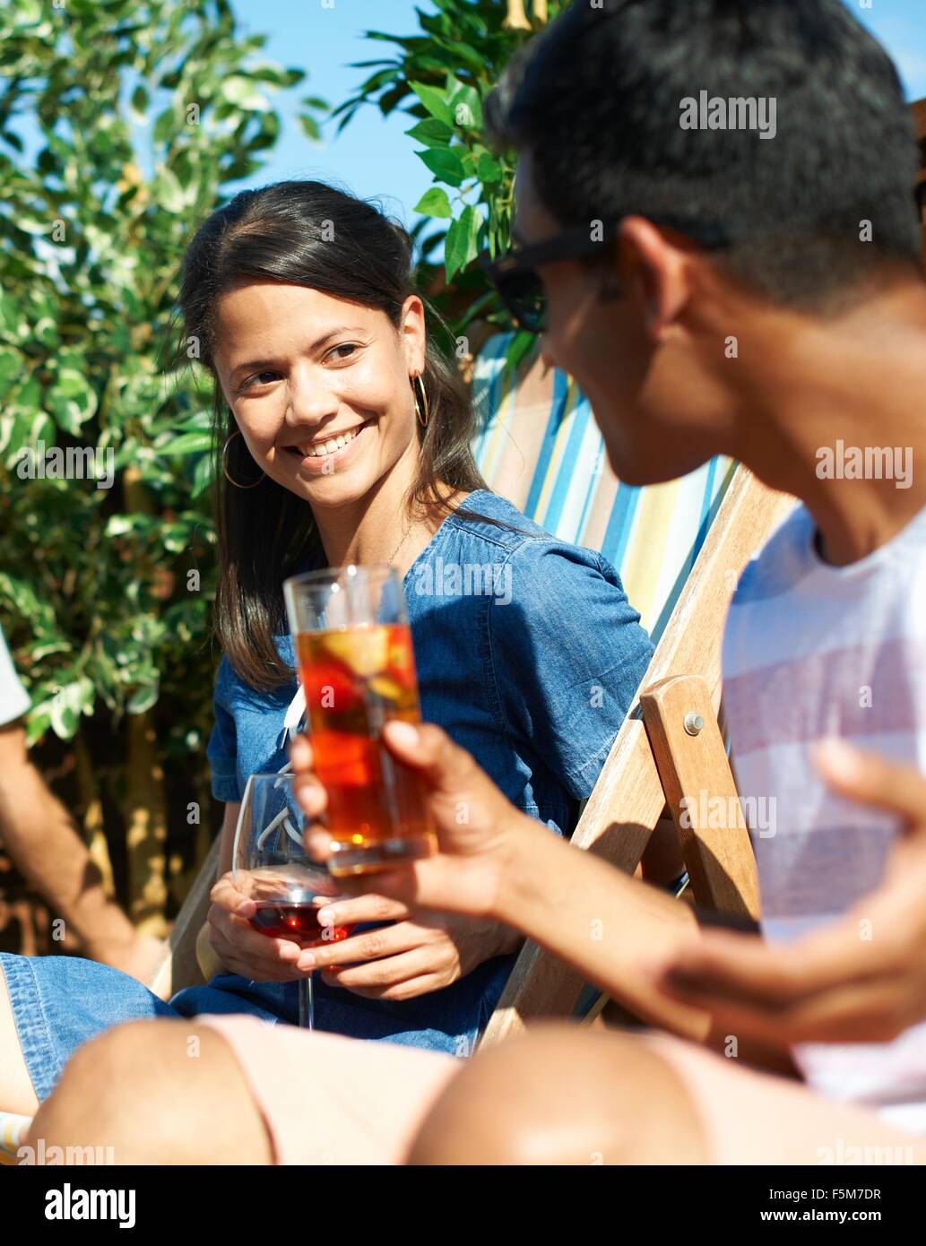 L'homme et la femme assis sur des transats talking at rooftop party Banque D'Images