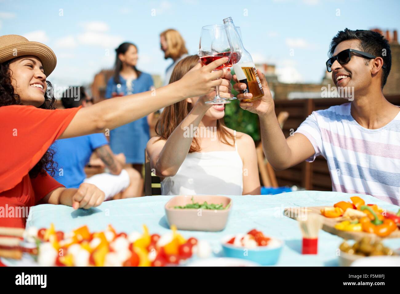 Amis, hommes et femmes de faire un toast at rooftop barbecue Banque D'Images