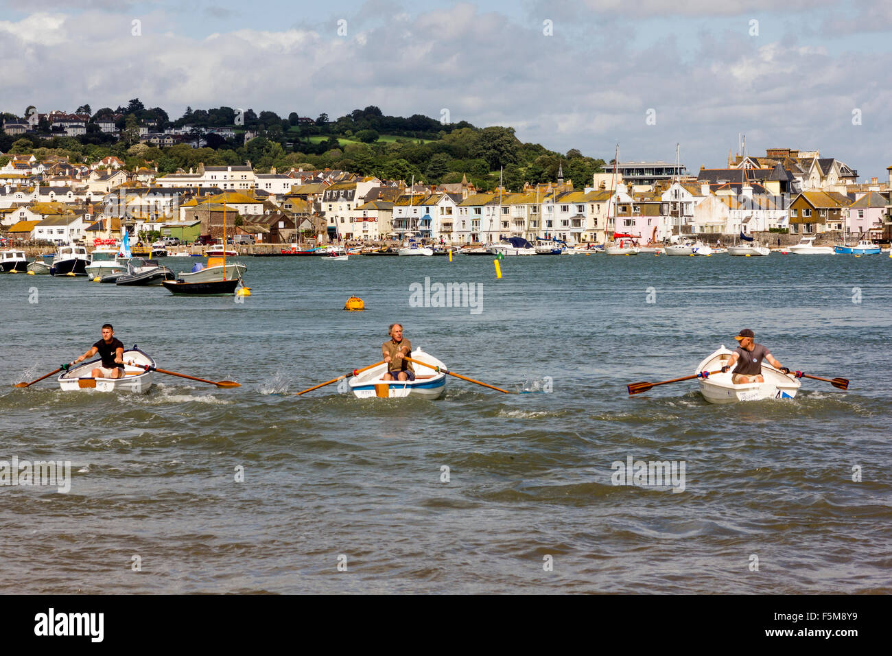 Trois hommes Tirer fortement sur leurs avirons comme ils leurs bateaux de course autour de la rivière Teign Cours à Shaldon régate. Banque D'Images Trois hommes Tirer fortement sur leurs avirons comme ils leurs bateaux de course autour de la rivière Teign Cours à Shaldon régate. Banque D'Images