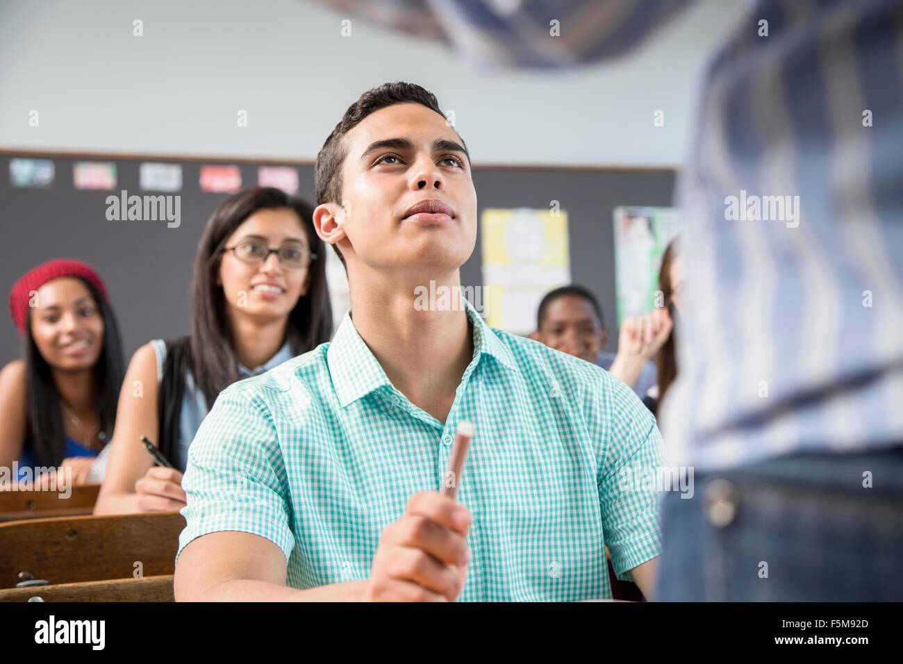 Male student listening to teacher in classroom Banque D'Images