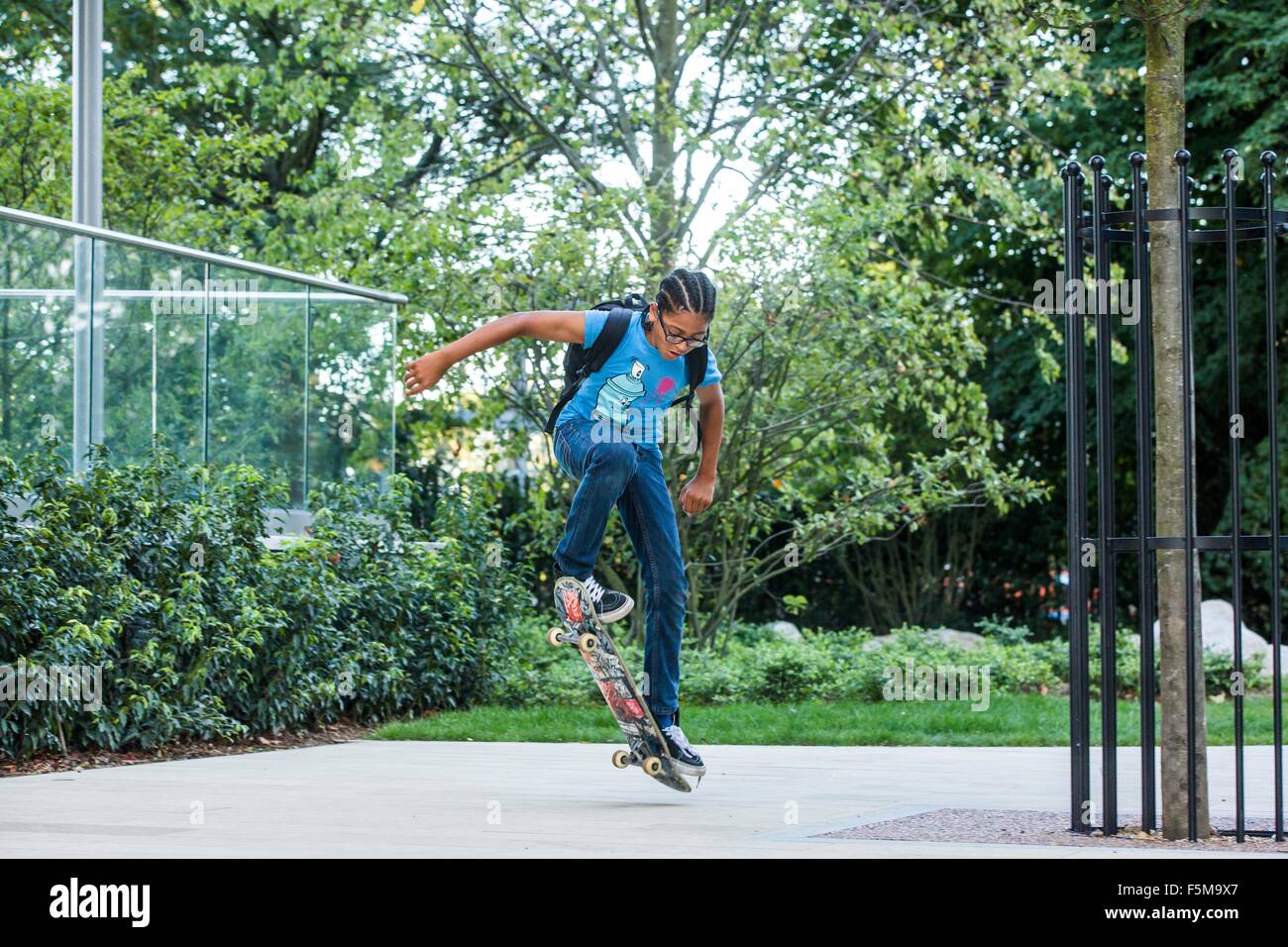 Boy doing skateboard trick sur trottoir urbain Banque D'Images