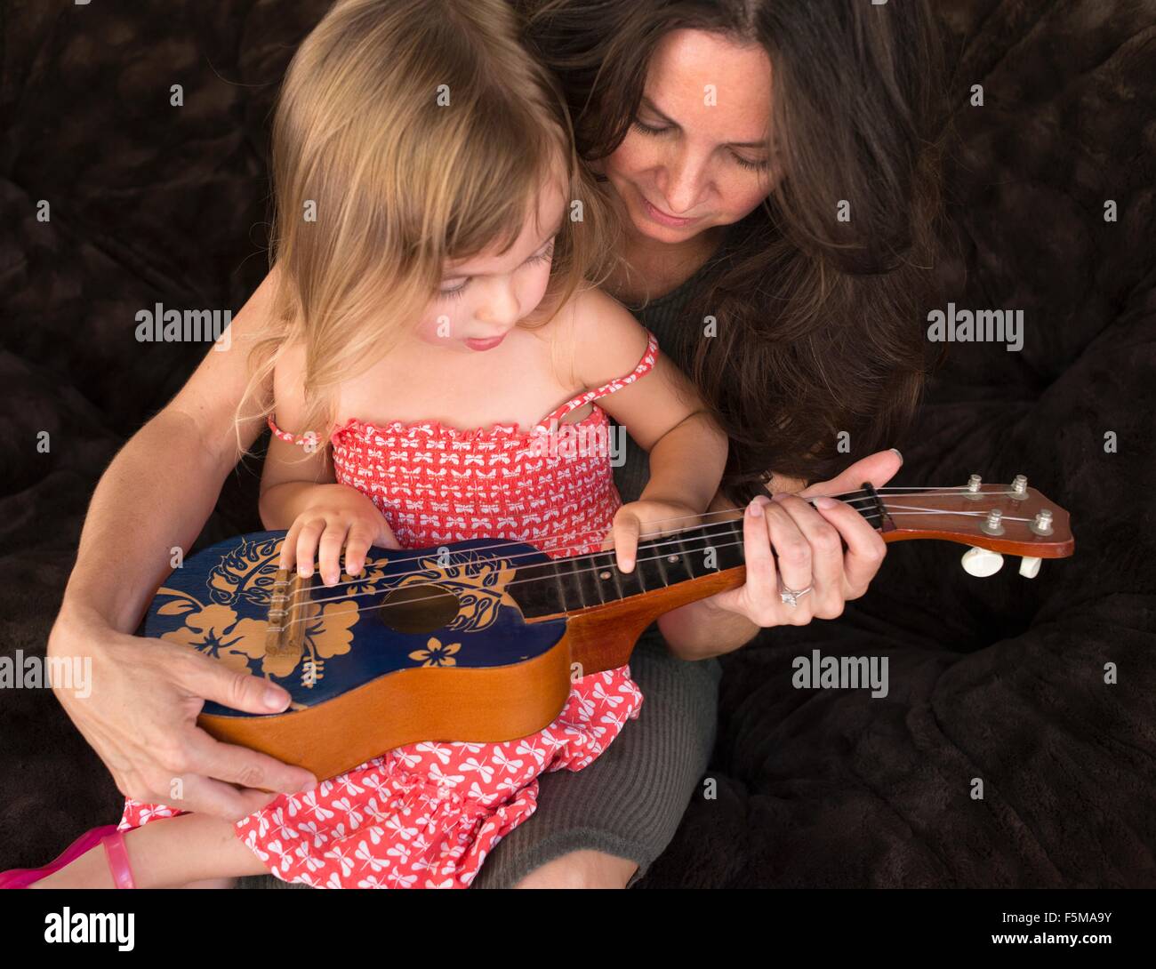 L'enseignement de mère fille à jouer le ukulele Banque D'Images