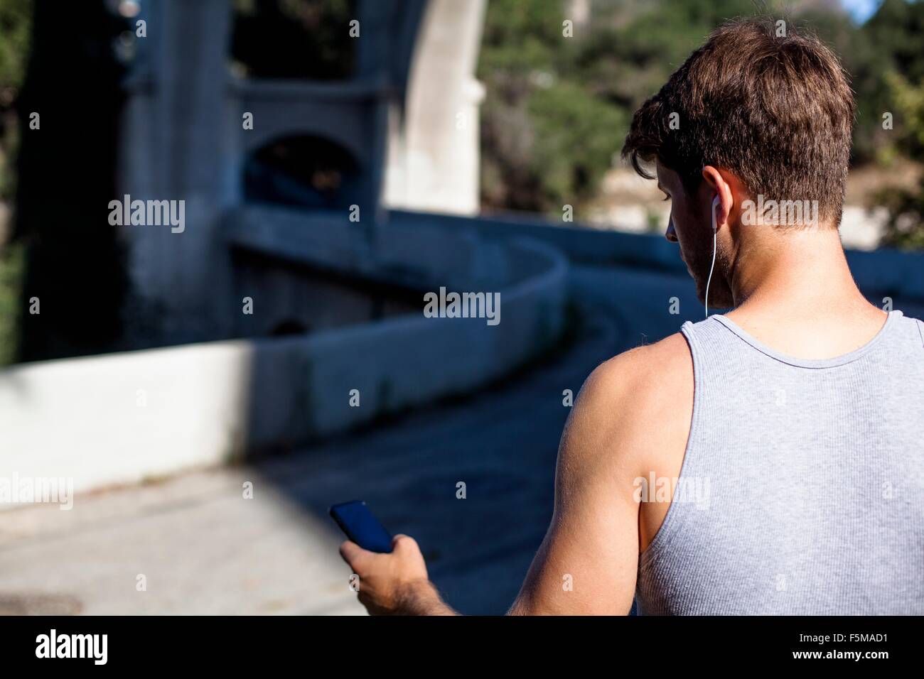 Jogger sélection de musique sur smartphone, Arroyo Seco, Pasadena, Californie, USA Banque D'Images