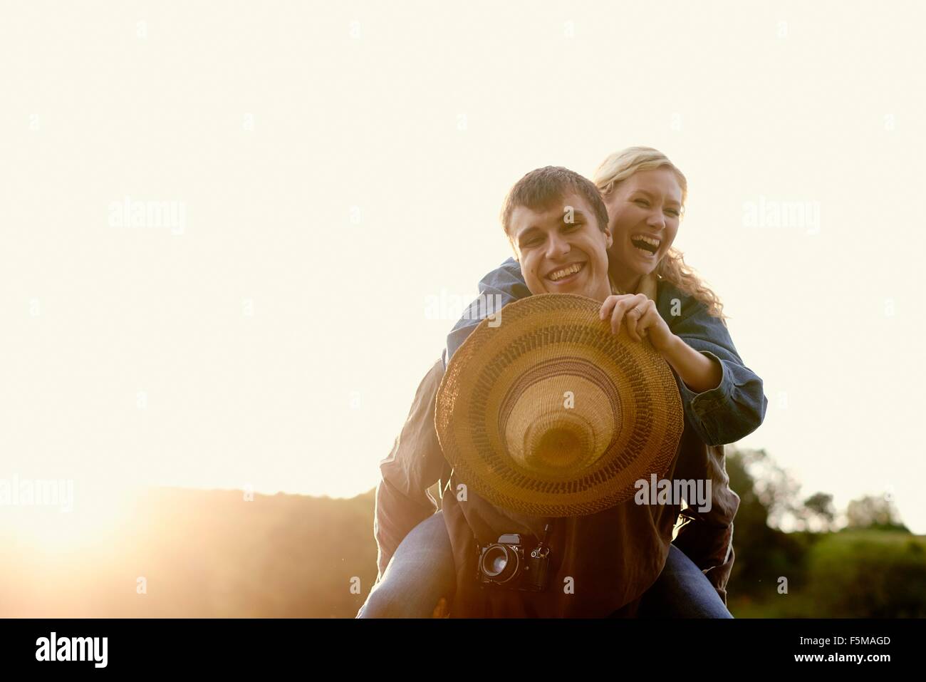 Portrait of young man giving girlfriend a piggyback Banque D'Images