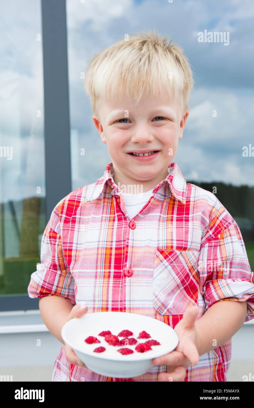 Portrait de garçon sur patio avec bol de framboises Banque D'Images