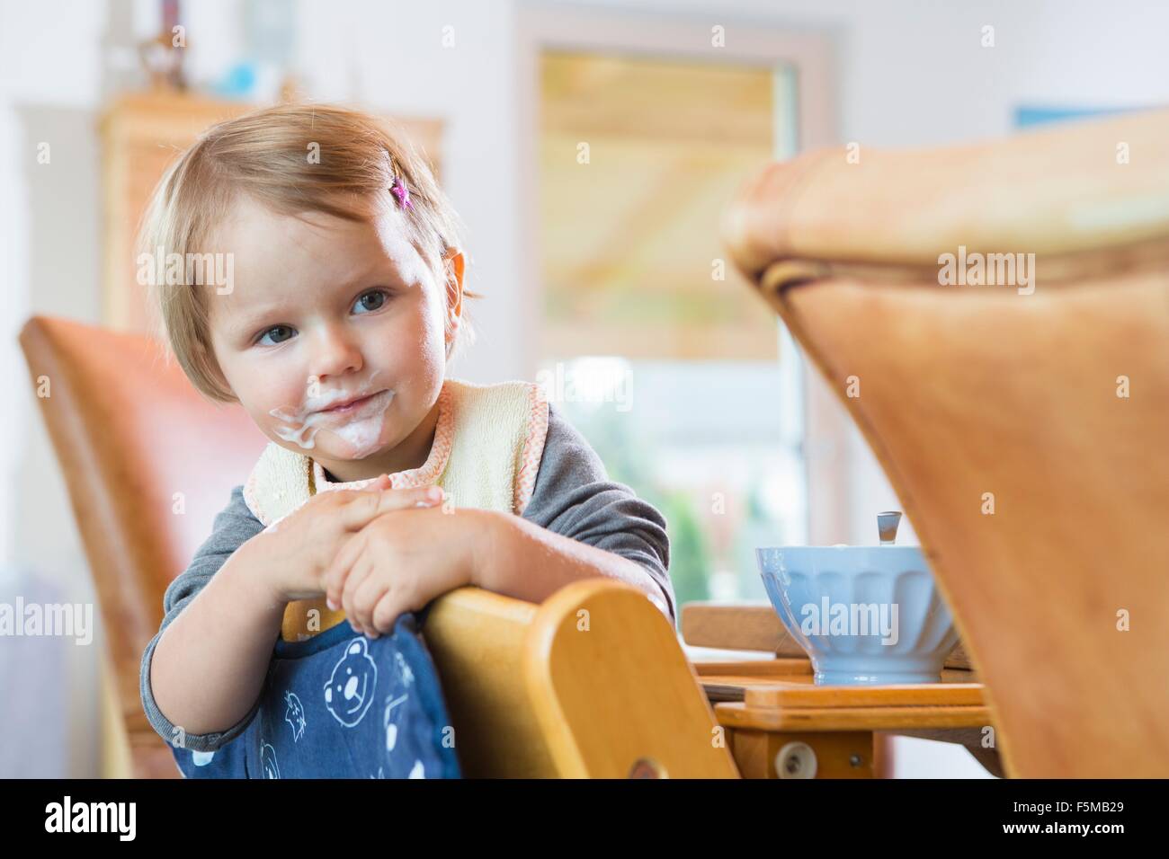 Portrait of female toddler appuyée sur une chaise de salle à manger Banque D'Images